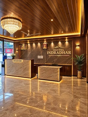 A hotel reception area with a marble reception desk, a chandelier, and a sign reading 'HOTEL INDRADHAR'. - Hotel Indradhar (Dharamshala)