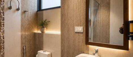 A modern bathroom with a toilet, bidet, sink, and mirror.