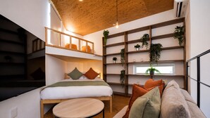 A compact room with a bunk bed, a round wooden table, and a sofa. - Olive Stay Osaka (Osakashi nishiku)