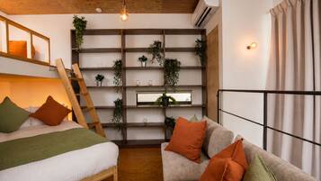 A room with a loft bed, a sofa, a ladder, shelves with plants, and a window with curtains.