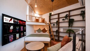 A modern bedroom with a loft bed, a TV displaying Netflix recommendations, and a wooden ceiling. - Olive Stay Osaka (Osakashi nishiku)