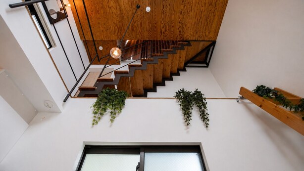 A modern staircase with wooden steps and metal railings, a hanging light fixture, and potted plants. - Olive Stay Osaka (Osakashi nishiku)
