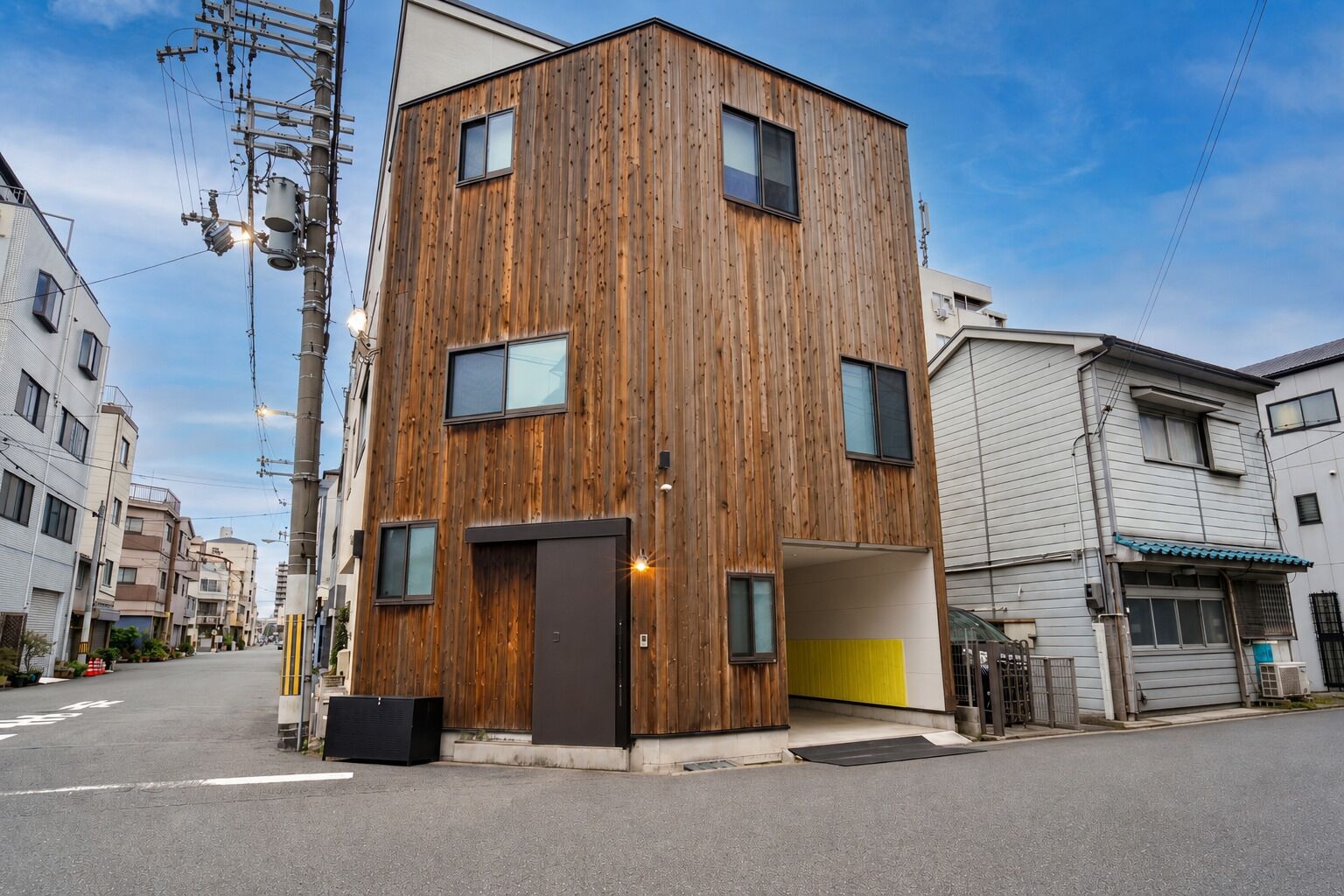 A modern multi-story building with a wooden facade, a garage entrance, and a visible street view.