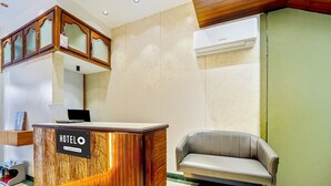 En hotellreception med en träpanel, en sittgrupp med läderklädsel och en luftkonditioneringsenhet på väggen.