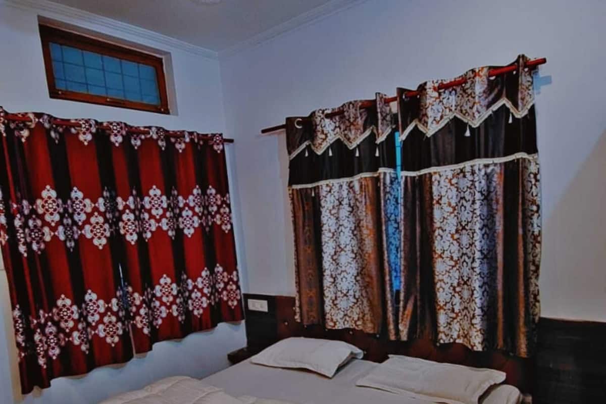 A bedroom with a bed, a ceiling fan, patterned curtains, and a window.