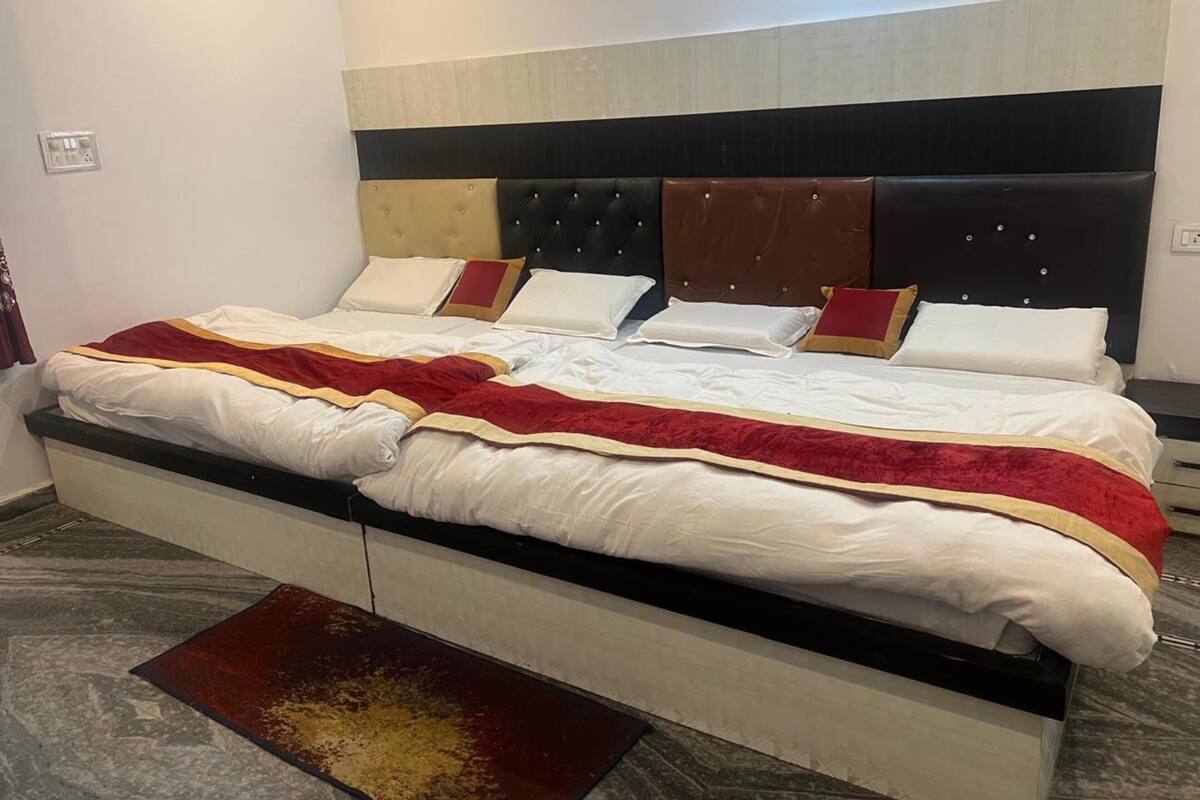 A double bed with a headboard, a bedside table, and a red and gold throw blanket.