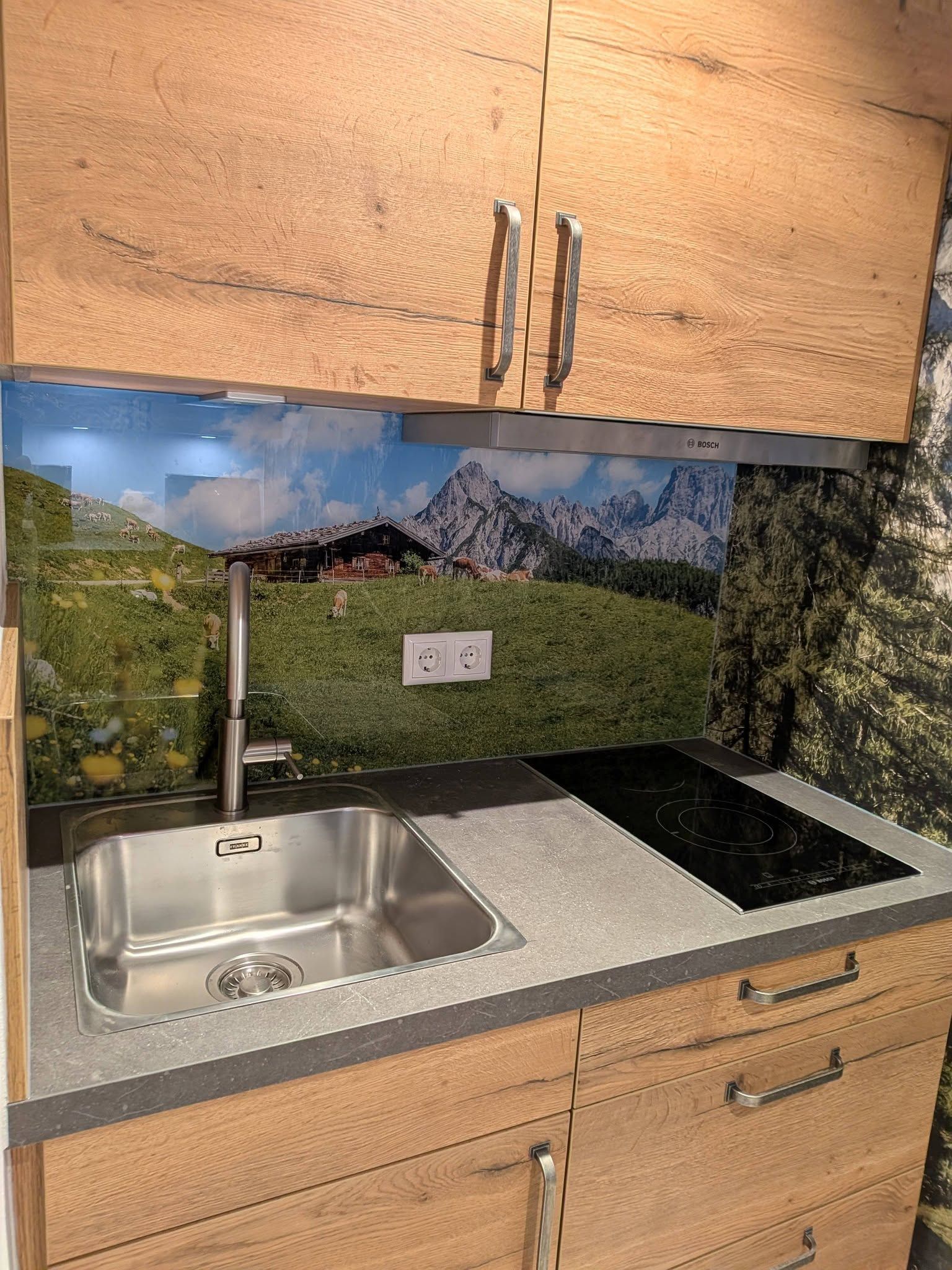 A kitchen with wooden cabinets, a stainless steel sink, and a black electric stove.