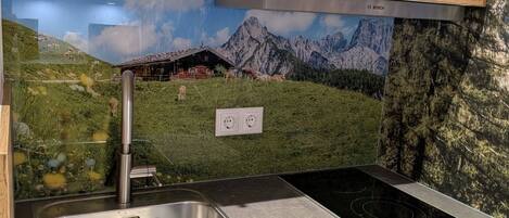A kitchen with wooden cabinets, a stainless steel sink, and a black electric stove.