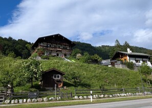 Eine Berglodge mit einem großen Holzhaus, einer kleineren Holzhütte und einer Steinmauer.
