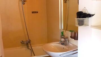 A bathroom with a bathtub, a sink, a toilet, a mirror, and a shower.