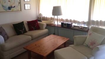 A living room with a sofa, armchair, wooden coffee table, lamp, and a radiator.