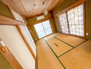 Una stanza con tatami, porte scorrevoli e una ventola a soffitto.