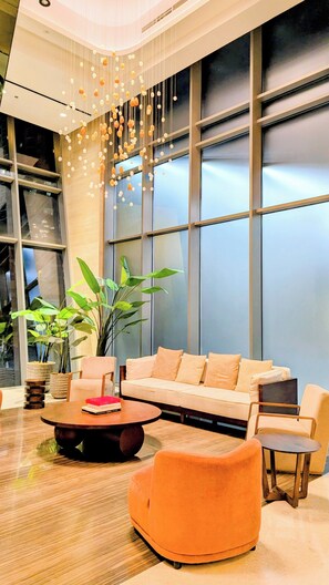 Eine moderne Lobby mit einer Couch, Sesseln, einem Couchtisch und einer Pendelleuchte.
