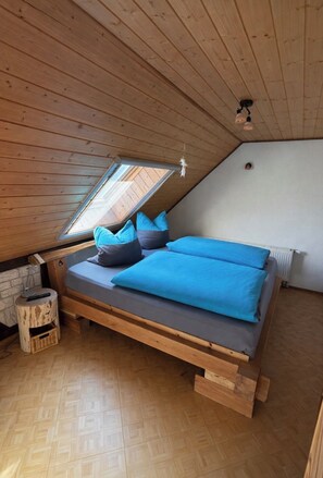A loft bedroom with a sloped ceiling, a wooden bed frame, a skylight, and a small side table. - Country House with Pool & 2 Fireplaces | Sleeps 10 | Huge Garden Near the Spreewald (Heideblick)