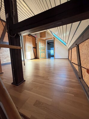 A spacious attic room with wooden flooring, exposed beams, and a skylight.