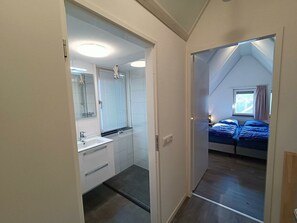 Ein Schlafzimmer mit Fenster, Bett und einem Badezimmer mit Waschbecken und Spiegel.