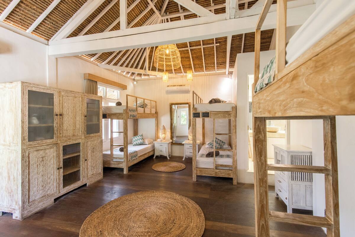 Una habitación rústica con muebles de madera, un techo alto y un tapete tejido en el suelo.
