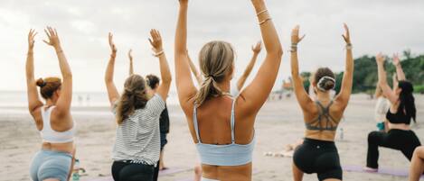 Un grupo de personas en tapetes de yoga en una playa.