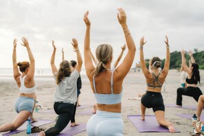 A group of people on yoga mats on a beach. - Kima Surf Camp Seminyak (Seminyak)