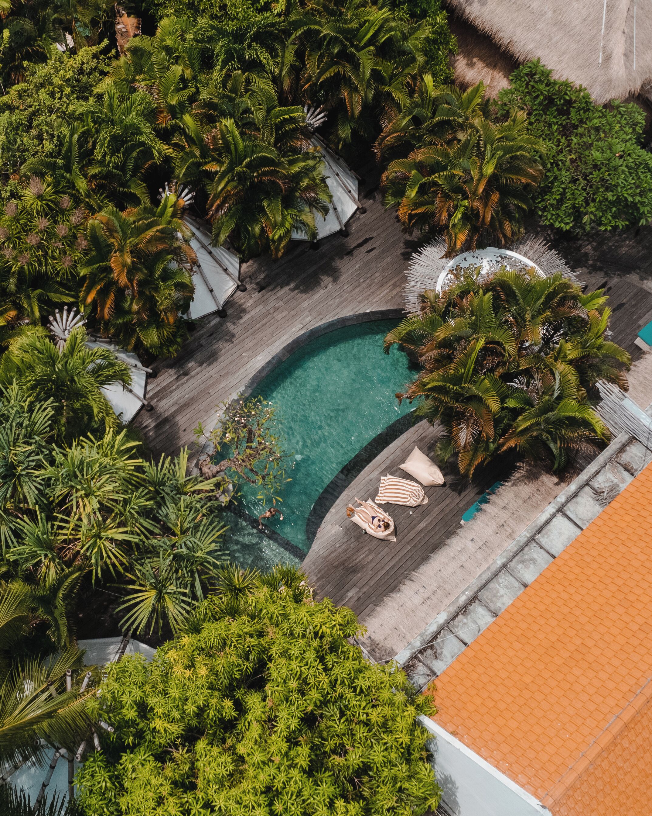 Ein Luftbild eines Resorts mit Swimmingpool, umgeben von Palmen und Liegestühlen.