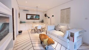 A modern interior with a dining area, a sofa, and a unique wooden cart. - Kima Surf Camp Bali Seminyak (Seminyak)