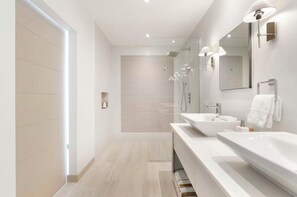 Een moderne badkamer met twee wasbakken, een grote spiegel en een douchehoek.