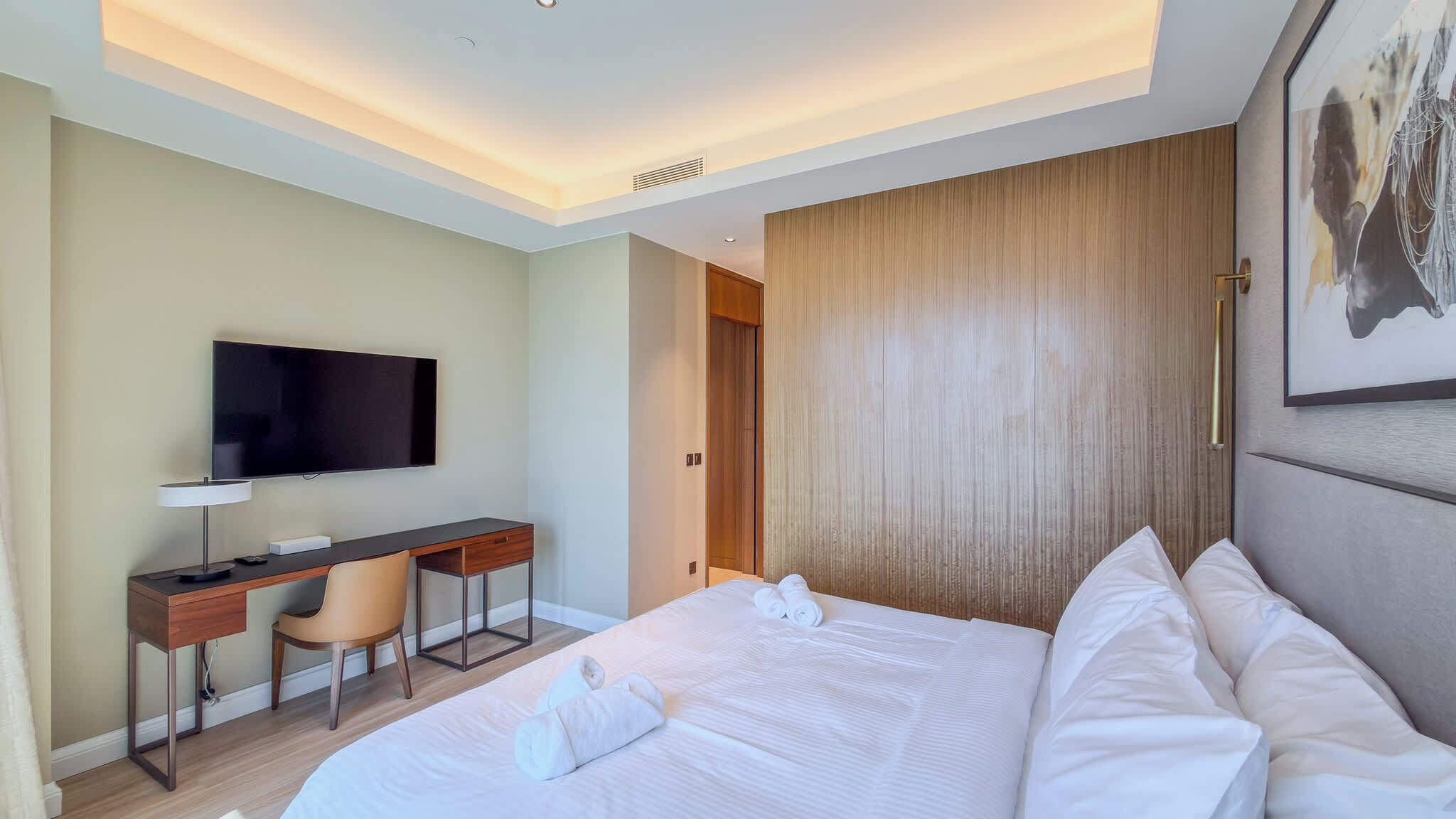 Ein Hotelzimmer mit einem Bett, einem Schreibtisch mit Stuhl, einem Fernseher und einer Tür.