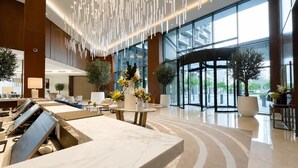 A modern lobby with a marble reception desk, large windows, and a revolving door. - Address Opera 1BR, Boulevard View-Hotel Style Stay (Dubai)