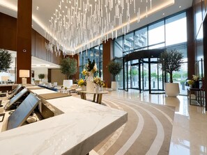 Eine moderne Lobby mit einer Marmorrezeption, großen Fenstern und einer Doppeltür.