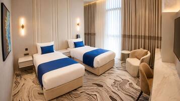 A hotel room with two beds, a seating area, and a television.