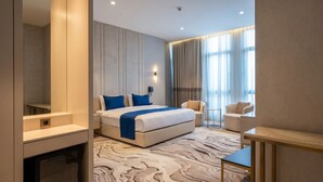 Una habitación de hotel moderna con una cama grande, un escritorio, una silla y una mesita.