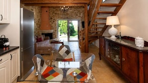 A kitchen with a built-in oven, a dining area with a glass table, and a staircase leading to an upper level.