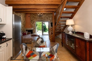 A kitchen with a built-in oven, a dining area with a glass table, and a staircase leading to an upper level.