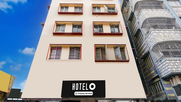 Een hotelgebouw met veel ramen en balkons, een bord dat aangeeft dat het een bedrijfsgerund hotel is, en een herkenbare architectuur met decoratieve details op de gevel.