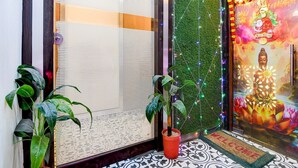 Een kamer met een groot raam, een groene wand en een Boeddhabeeld.