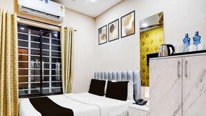 Een hotelkamer met een bed, een kledingkast, een raam met gordijnen en een wandairconditioner.