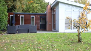 A modern building with a garage, outdoor seating, and a small tree. - Holiday Home in Brunssum With Terrace (Brunssum)