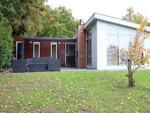 Ein modernes Gebäude mit Garage, Sitzgelegenheit im Freien und einem kleinen Baum.