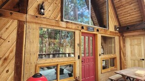 A wooden cabin with a red door, large windows, a Cuisinart appliance, and a wooden deck. - Mohawk Vista A-Frame Cabin (Blairsden-Greagle)