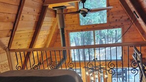 A wooden cabin with a loft bedroom, a ceiling fan, and a view of the forest. - Mohawk Vista A-Frame Cabin (Blairsden-Greagle)