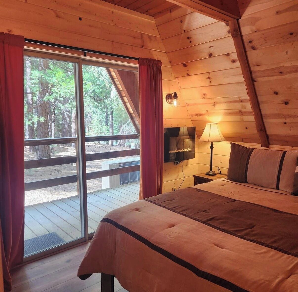 Une chambre à coucher avec un lit, une table de chevet, une lampe et une grande fenêtre avec des rideaux.