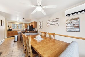 Un comedor con una mesa de madera, sillas y un ventilador de techo.