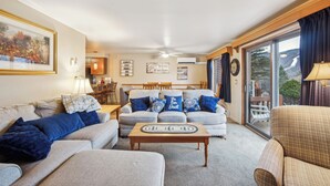 A living room with a sofa, a coffee table, and a dining area with chairs. - 2 Homes | Heated Pool + Game Room + Sauna | Mins to Gore Mountain (North Creek)