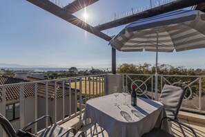 Un balcon avec une table, des chaises et une vue sur un terrain de sport.
