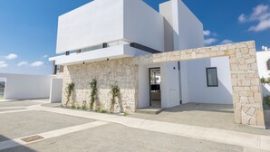 A modern building with a white facade, stone accents, and a clear sky. - New 4 Bedroom Villa With Pool, 100 Meters From the Beach (Paralimni)