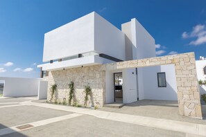 A modern building with a white facade, stone accents, and a clear sky. - New 4 Bedroom Villa With Pool, 100 Meters From the Beach (Paralimni)