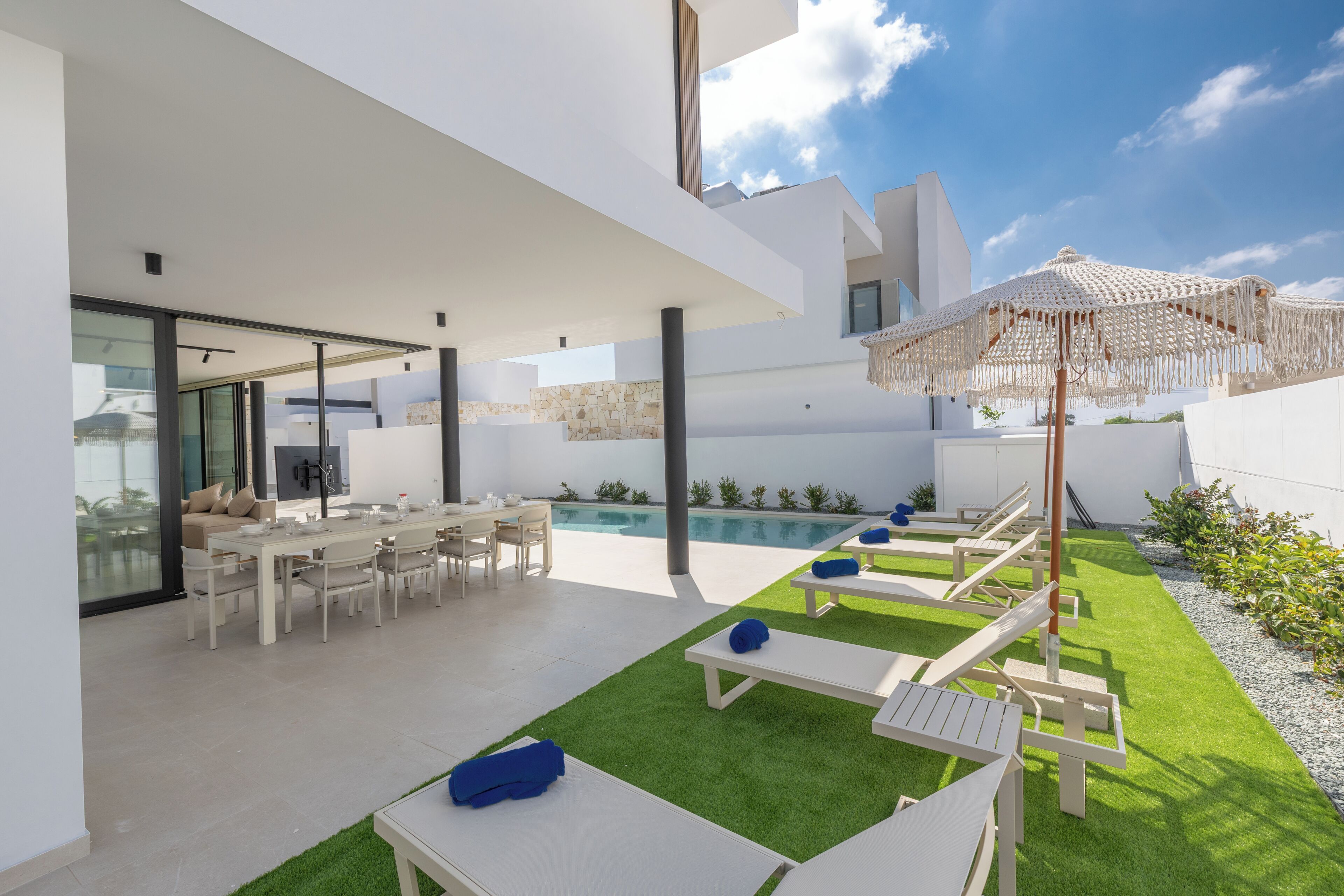A modern outdoor patio with a pool, dining area, and lounge chairs.