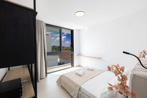 A modern hotel room with a bed, a desk, a large window with a city view, and a ceiling light. - New 4 Bedroom Villa With Pool, 100 Meters From the Beach (Paralimni)
