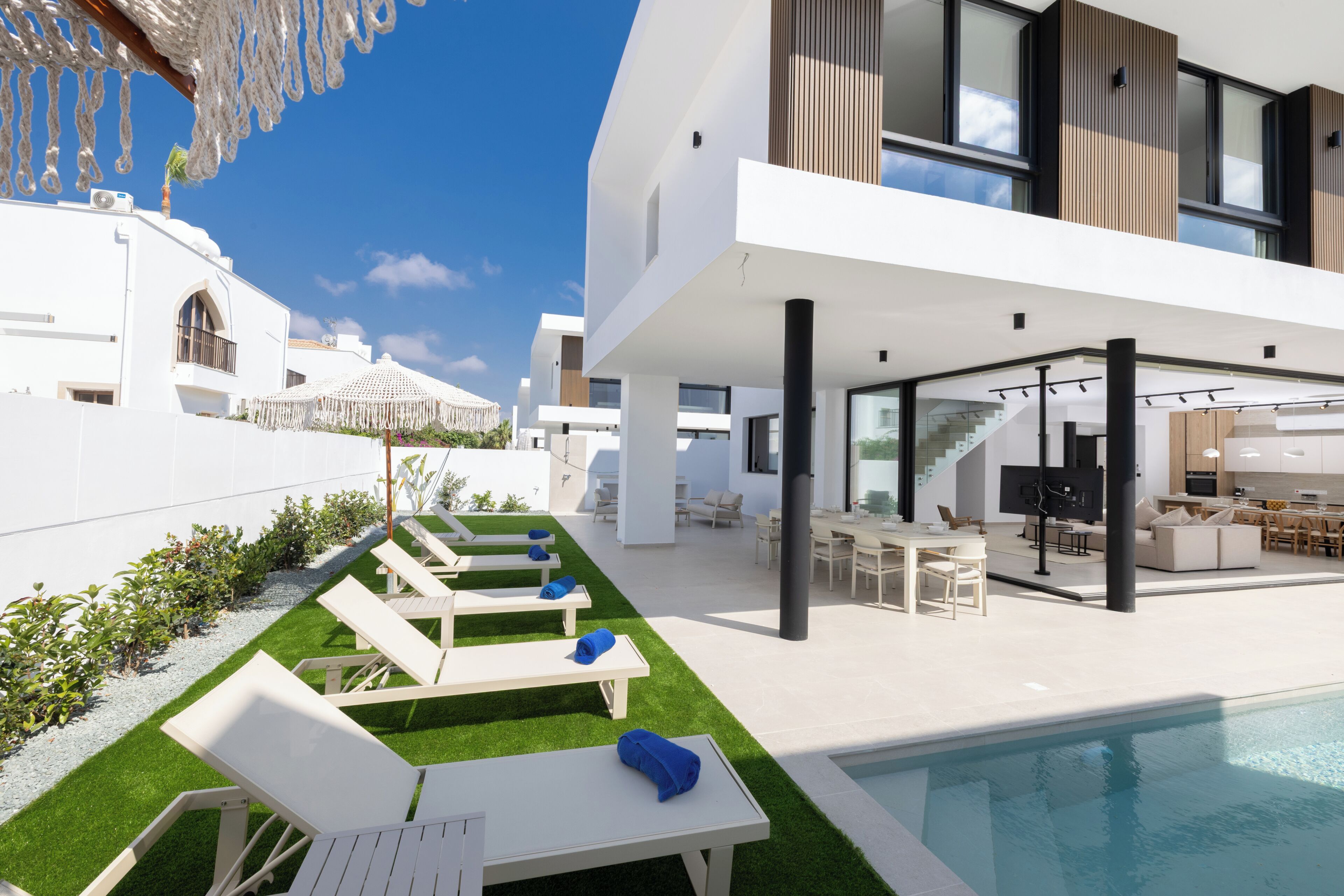 A modern outdoor pool area with lounge chairs and a dining area.