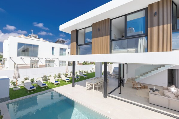 A modern two-story house with a swimming pool, outdoor seating, and a staircase. - New 4 Bedroom Villa With Pool, 100 Meters From the Beach (Paralimni)